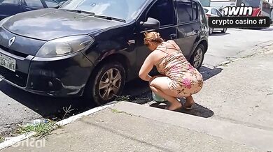 Uma mulher atraente lava o carro se exibindo na rua em cenas explícitas.